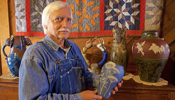 man in overalls holding pottery