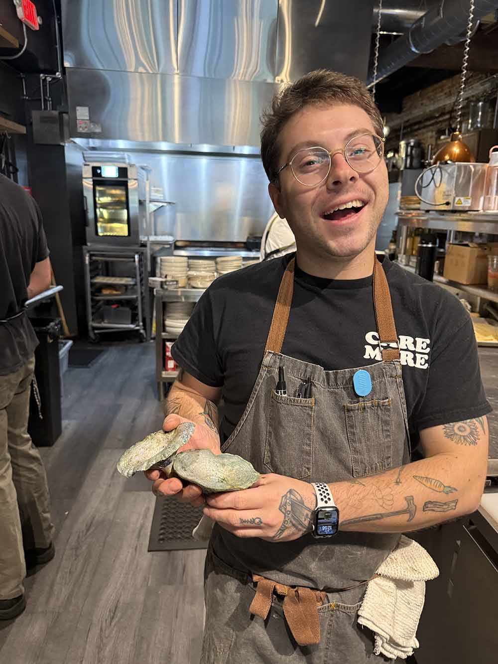 man holding clam shells in a kitchen 