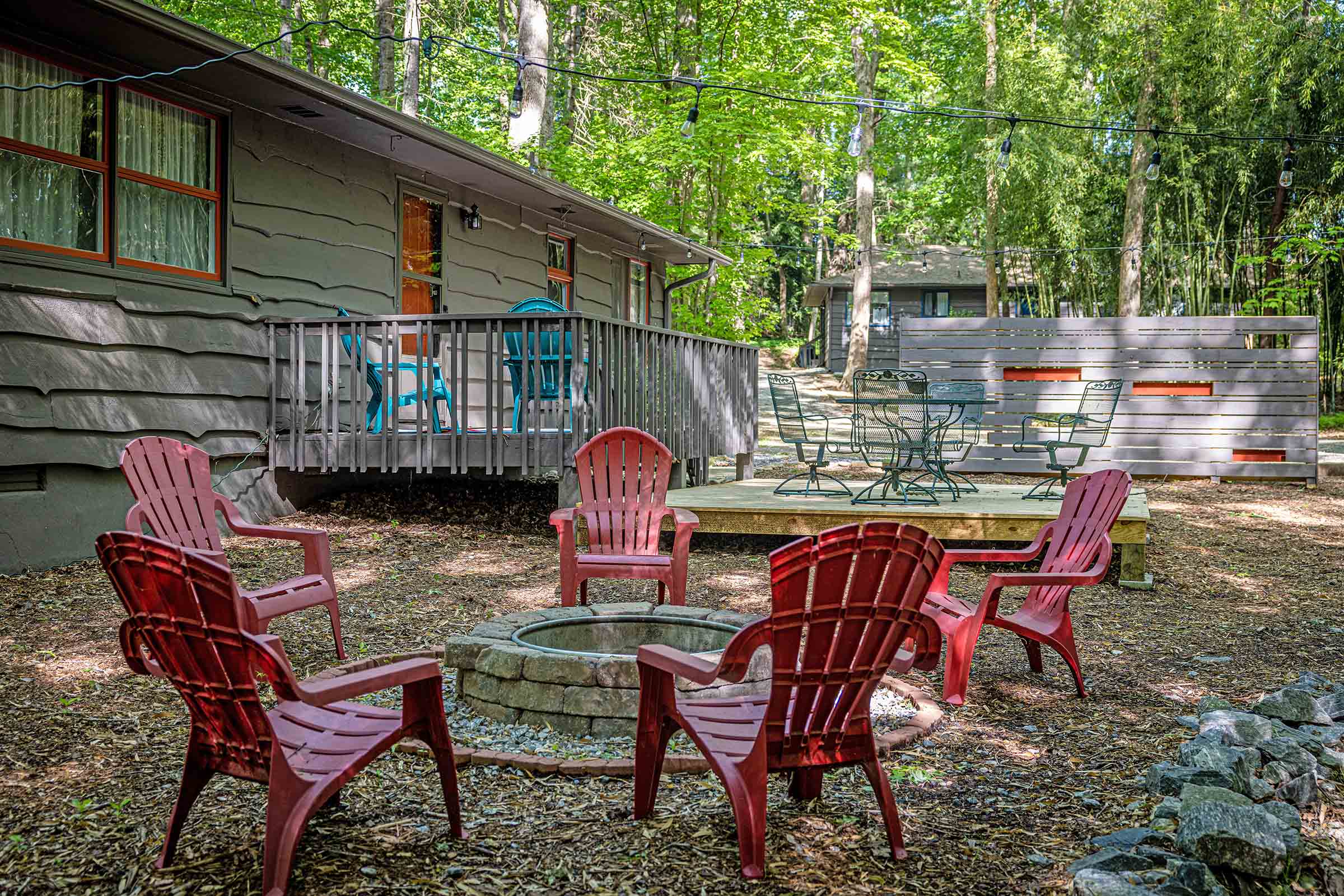 red Adirondack chairs surrounding a firepit without a fire