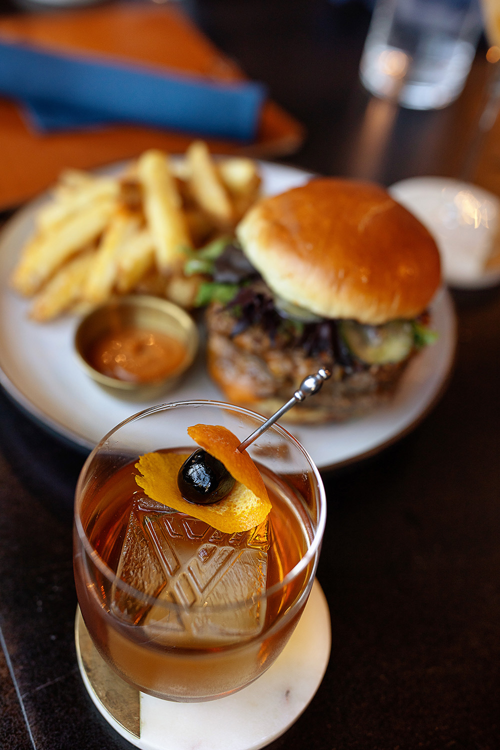 table with cocktail drink and burger with fries