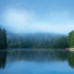 mountain lake surrounded by trees with clouds