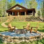 vacation home with a fireplace in the front yard with three chairs